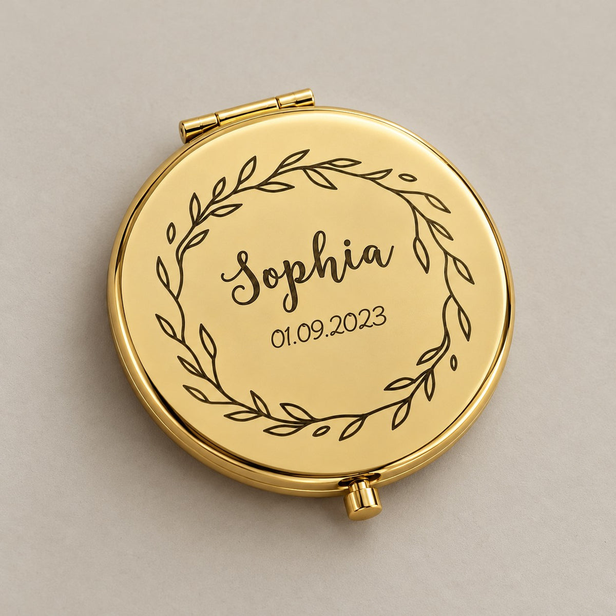 Engraved compact mirror on a greige surface
