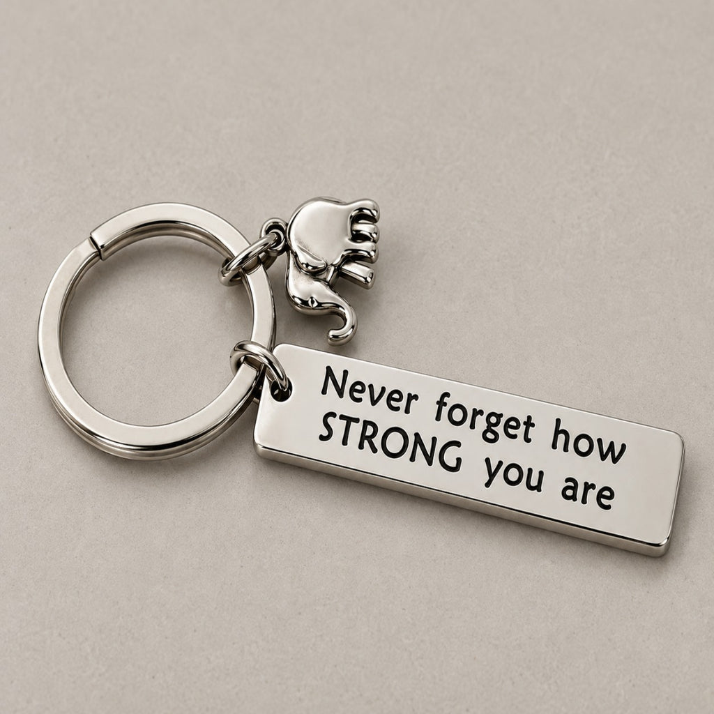 Never forget how strong you are keychain on a greige surface