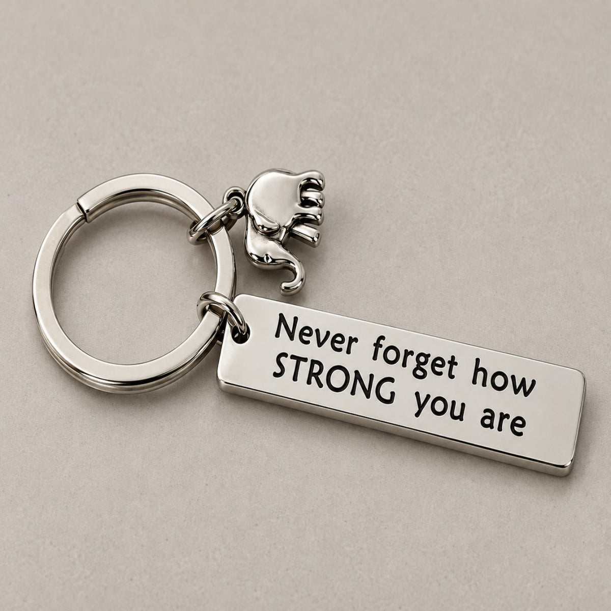 Never forget how strong you are keychain on a greige surface