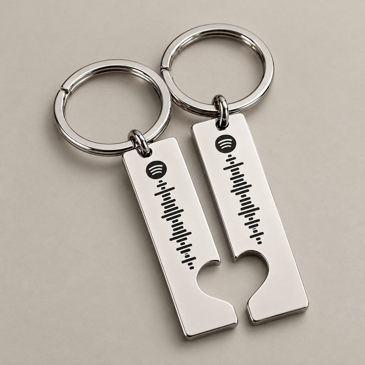 Matching silver Spotify scannable keyrings on a neutral surface