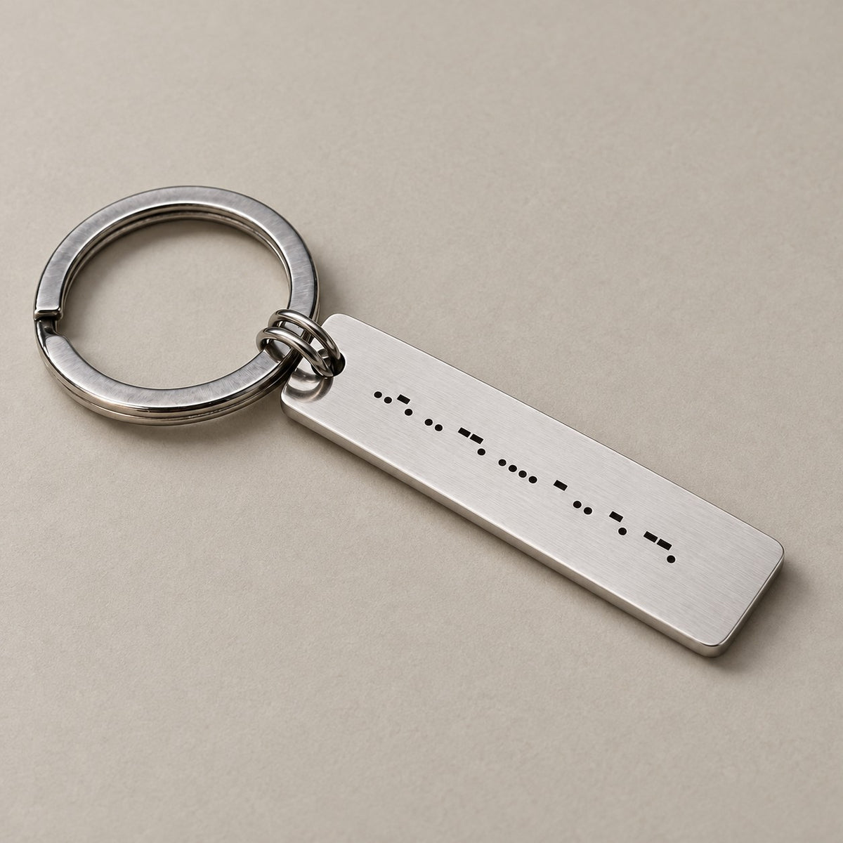 Personalised morse code keychain on a greige surface